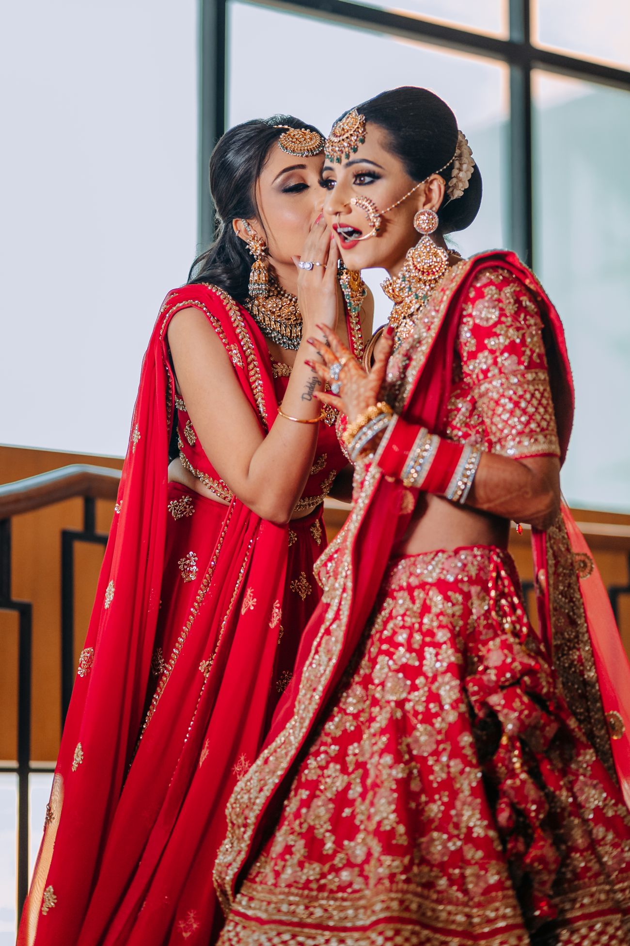 bride and her sister in red lehengas