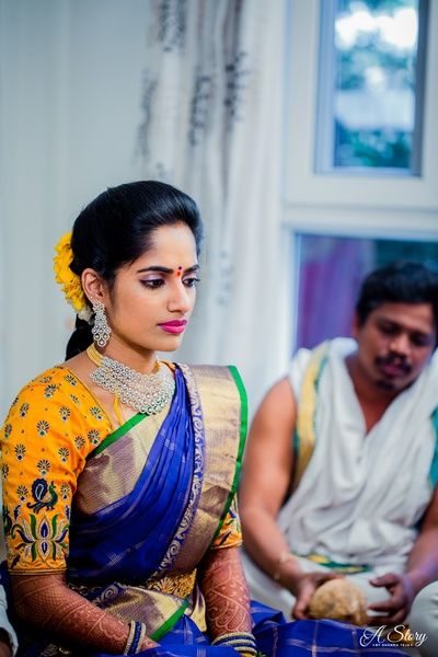 Photo of South Indian bride wearing a royal blue saree with a purple blouse.
