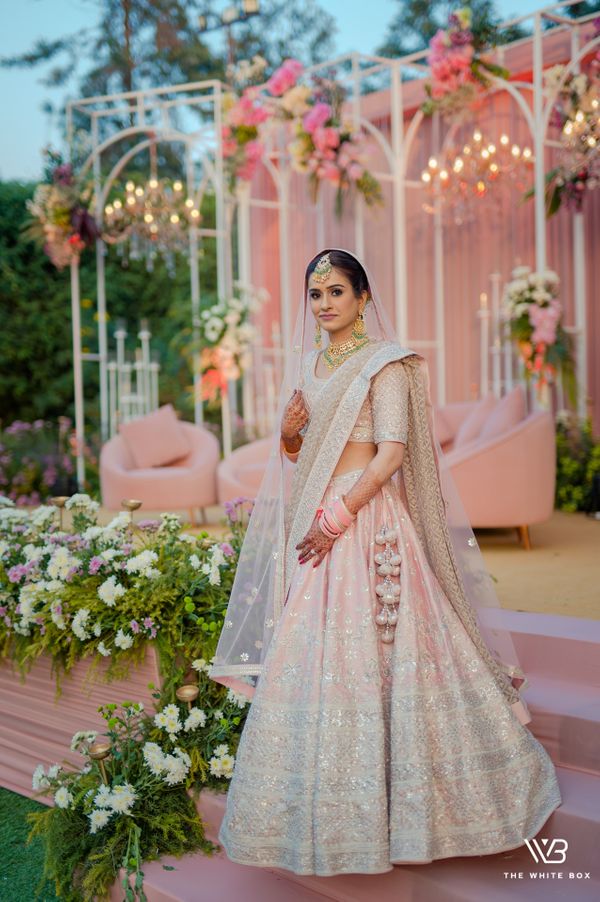 Photo of A picture of a happy bride dressed in red and pink bridal lehenga
