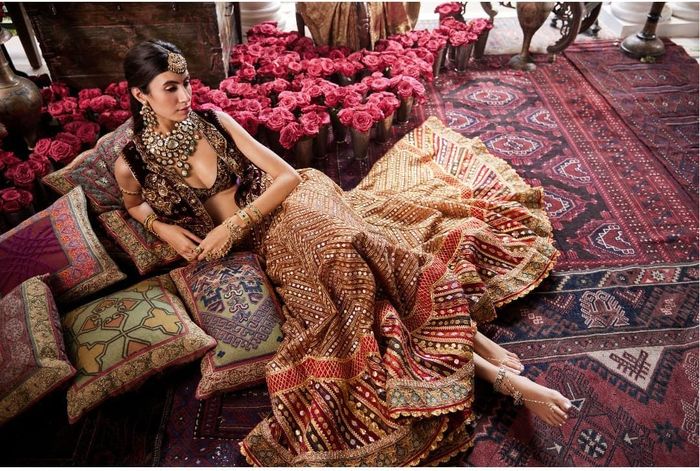 Rimple and Harpreet Narula - A deep red tulle and silk lehenga. The skirt  features floral vines and bejeweled peacocks derived from archival brocade  textiles, layered over multi-hued chevrons that are gleaned