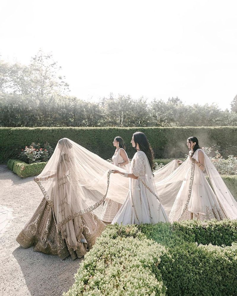 Bridesmaids holding a veil above the bride as she walks in