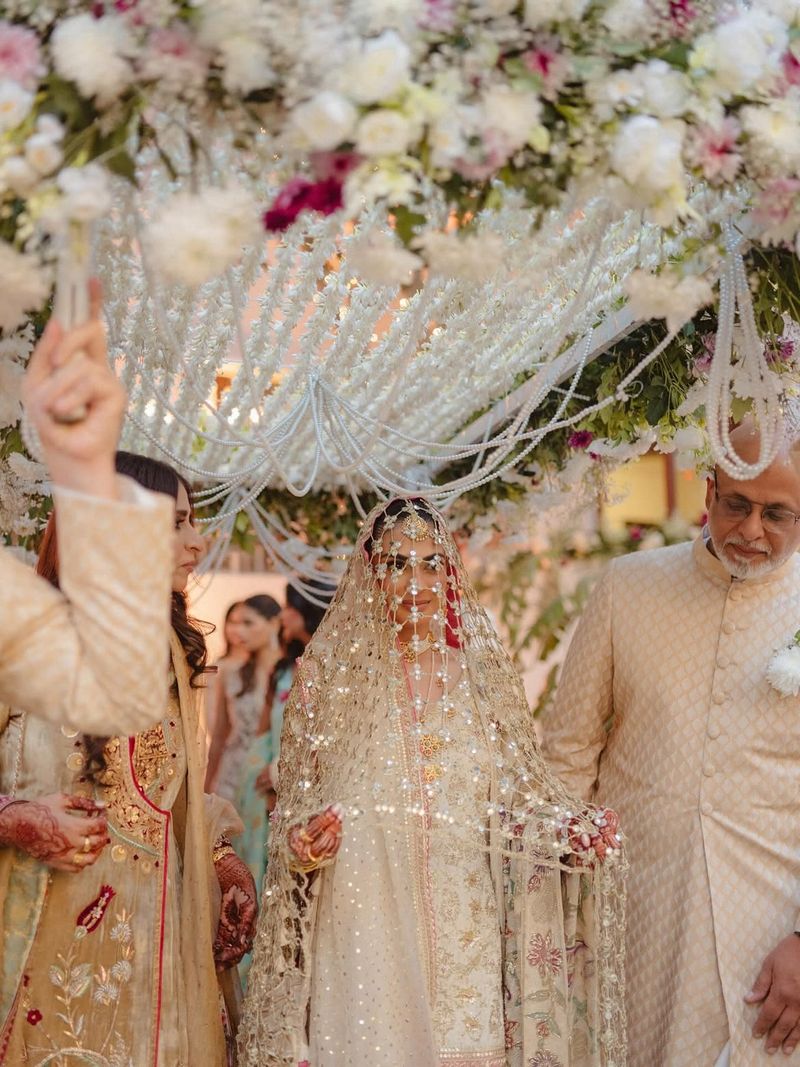 Bride walking under an embroidered mirror-work dupatta
