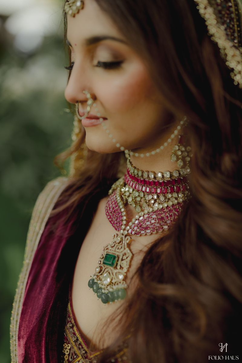 Layered emerald and diamond necklaces worn with a bridal outfit