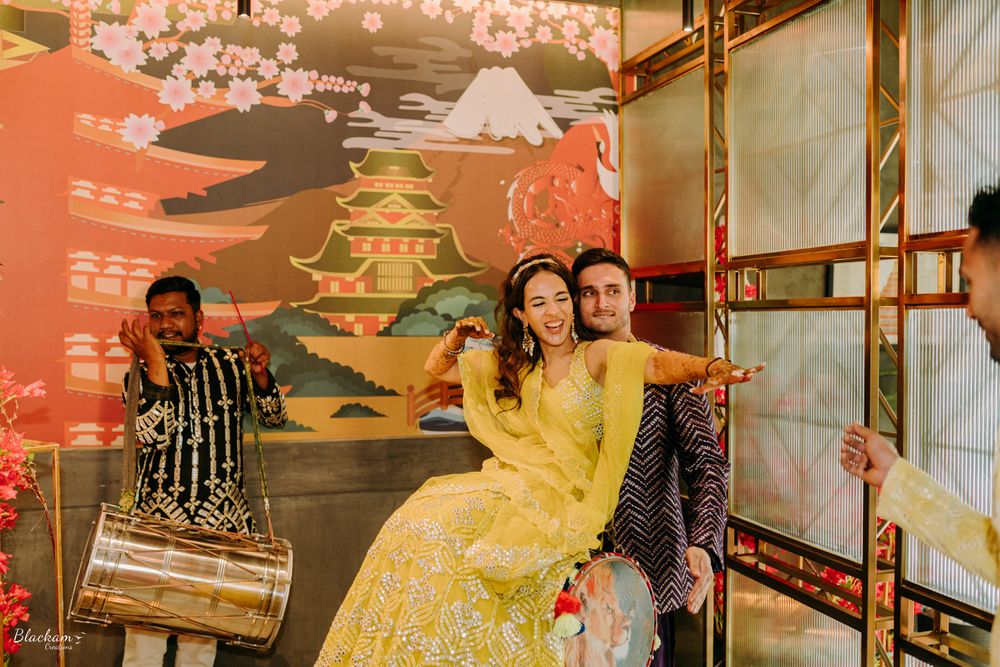 Photo of bride and groom having fun with dhol at mehendi