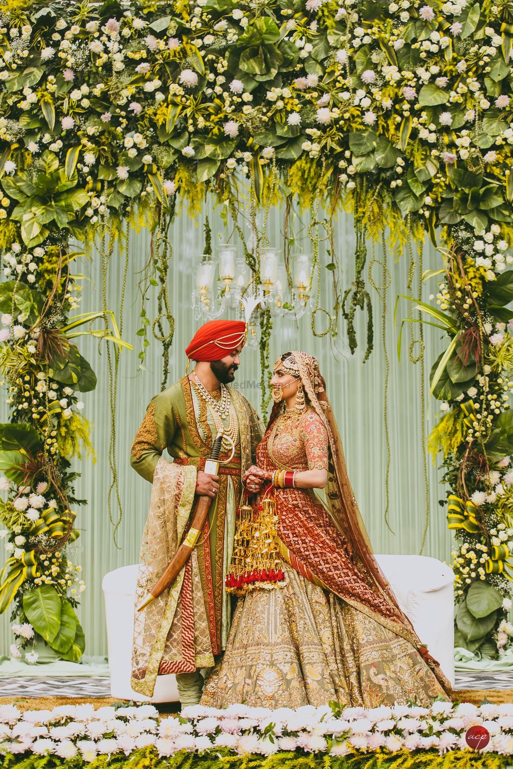 Photo of Coordinated bride and groom on stage decked up with unique floral arrangement