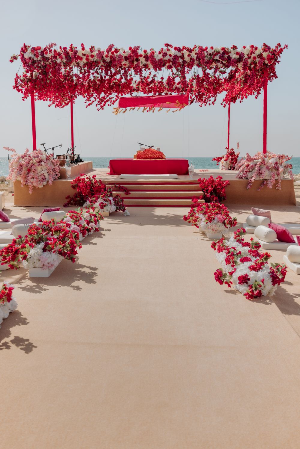 Photo of Pretty white and red outdoor mandap on the beachside with floral arrangements