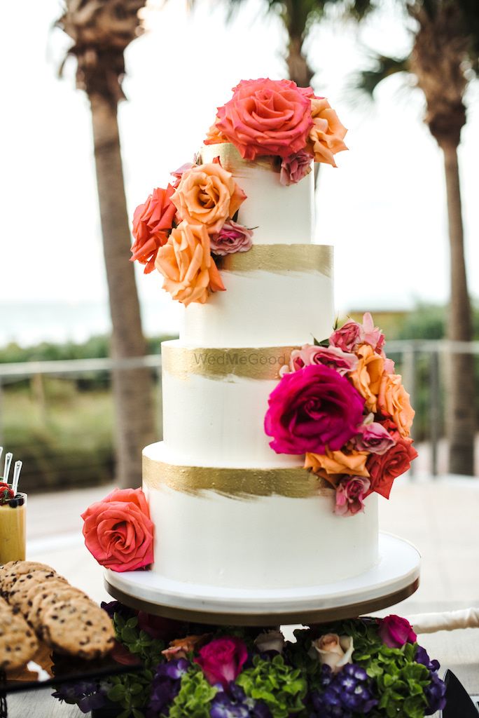 Photo of White and gold 4 tier wedding cake with flowers