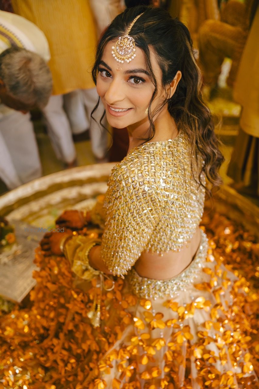 Photo of Gorgeous bridal portrait on her haldi day in that spectacular gold lehenga and a messy ponytail hairdo