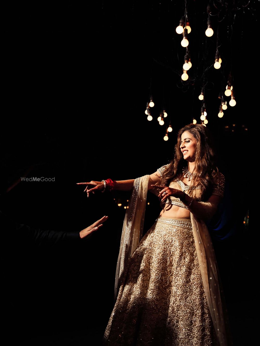 Photo of dancing bride shot in beige and gold lehenga on sangeet