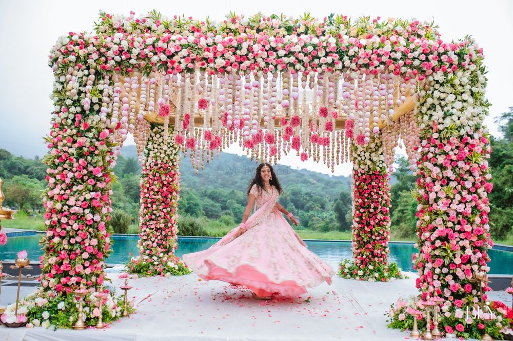 Photo of twirling bride under floral mandap