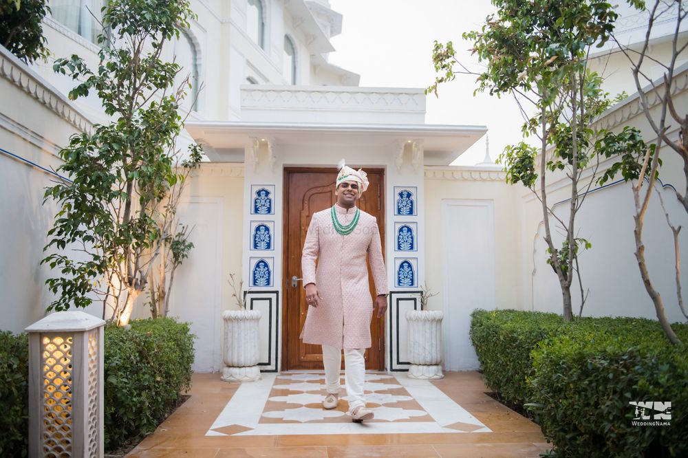Photo of A groom in a pink sherwani and contrasting green accessories