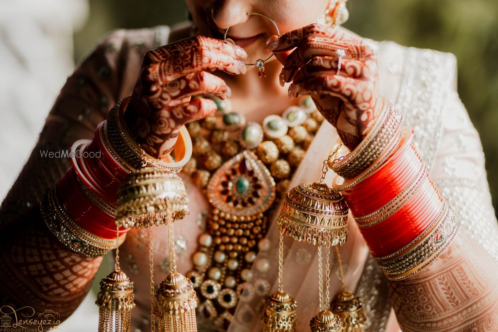 Photo of Bride putting on Nath in a full bridal ensemble