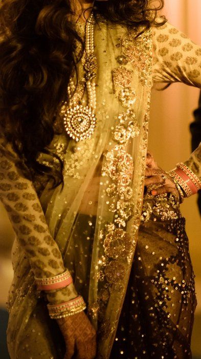 Photo of sabyasachi olive green sari with gold flower embrpidery and a printed gold blouse