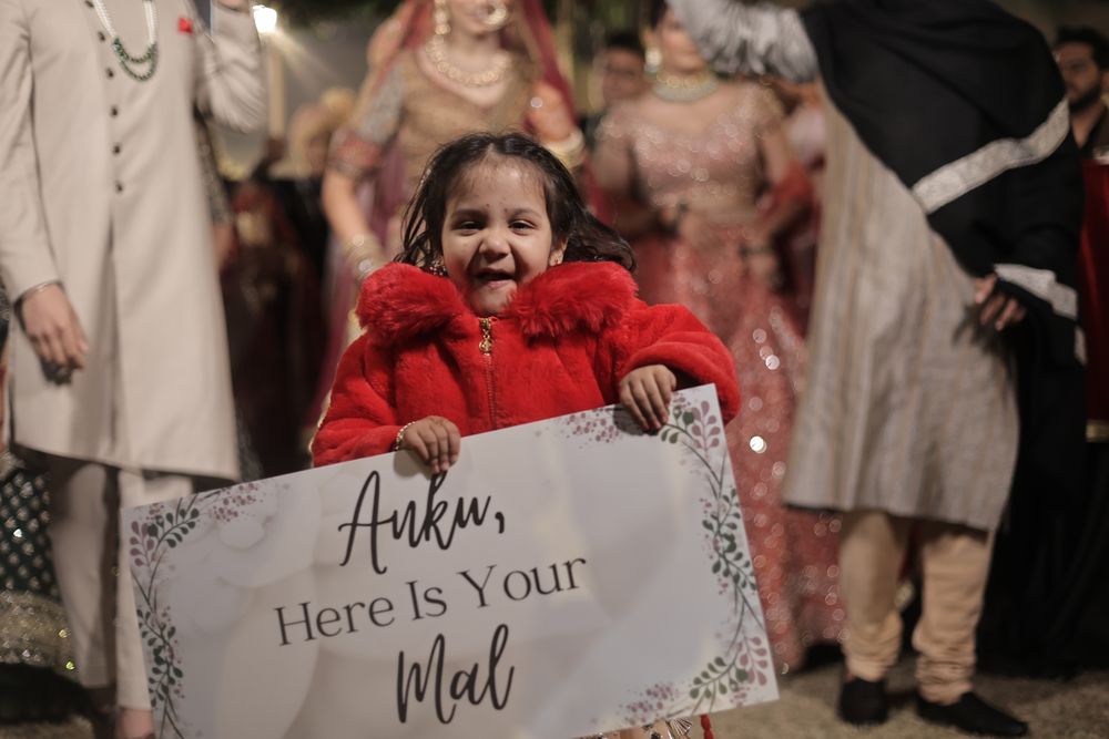 Photo of kid holding a cute placard during bridal entry with their wedding hashtag
