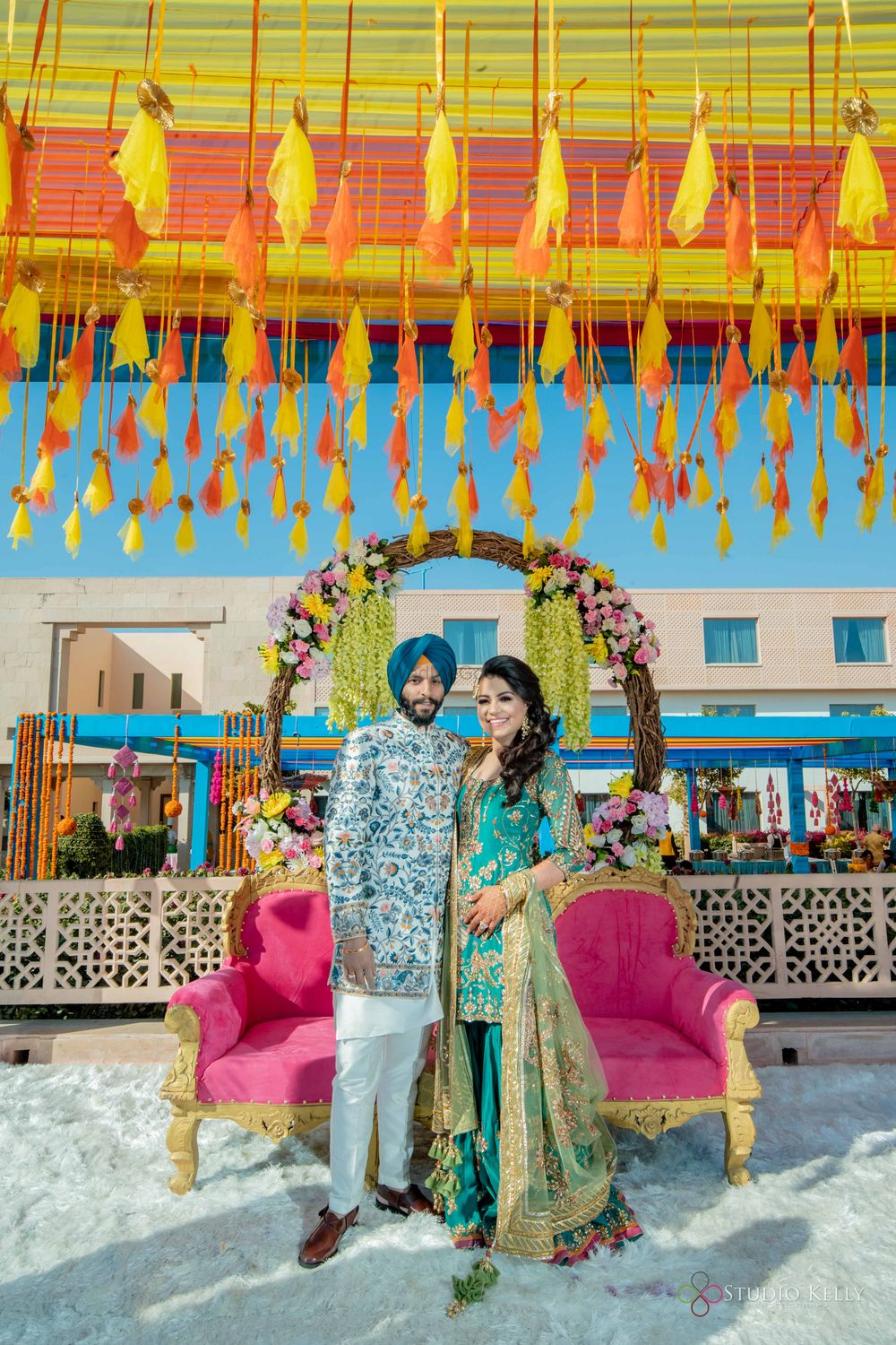 Photo of mehendi couple seat with tassel decor and floral arch