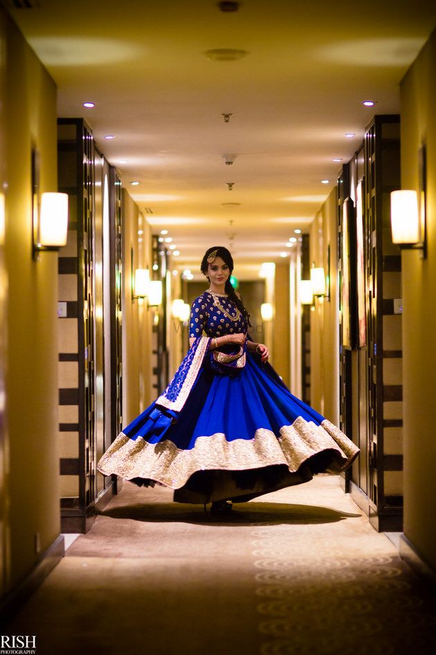 Photo of Bride twirling in blue and gold Sabyasachi lehenga
