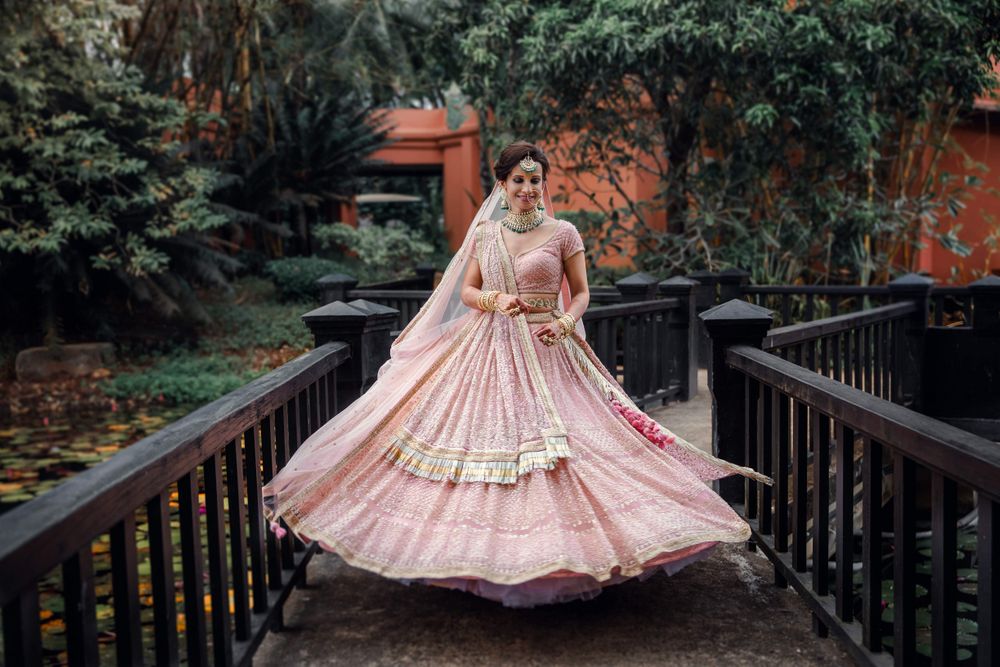 Photo of A bride in a millennial pink lehenga twirling happily.