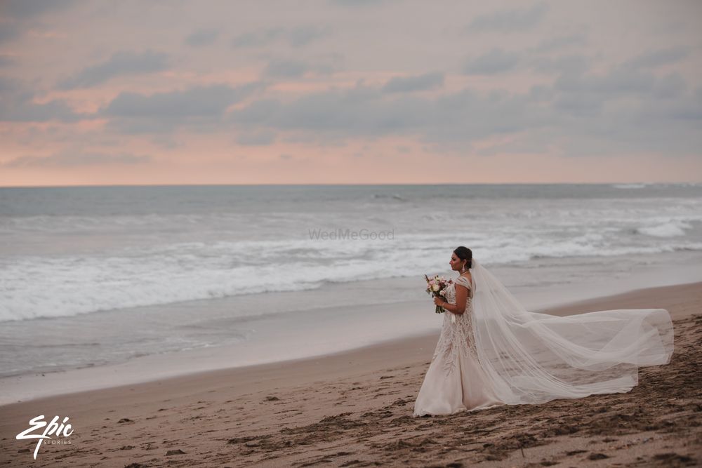 Photo of Bride on beach wearing gown with train