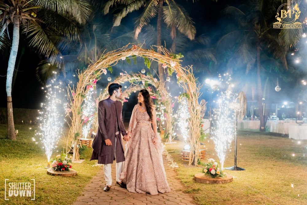 Photo of couple walking through entrance arch and sparklers on the side