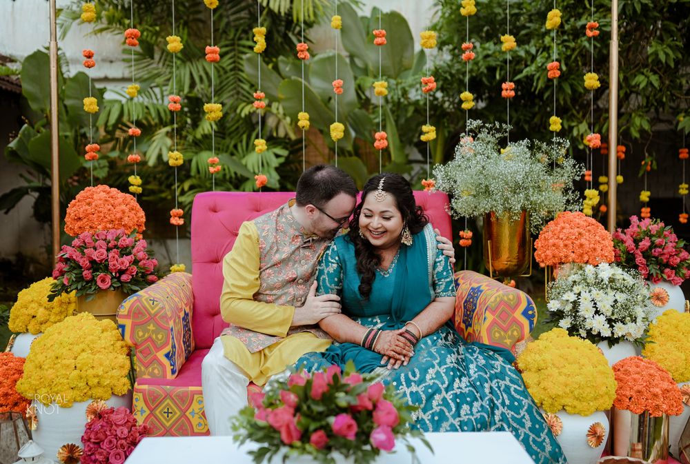 Photo of cute couple mehendi photo against floral string backdrop