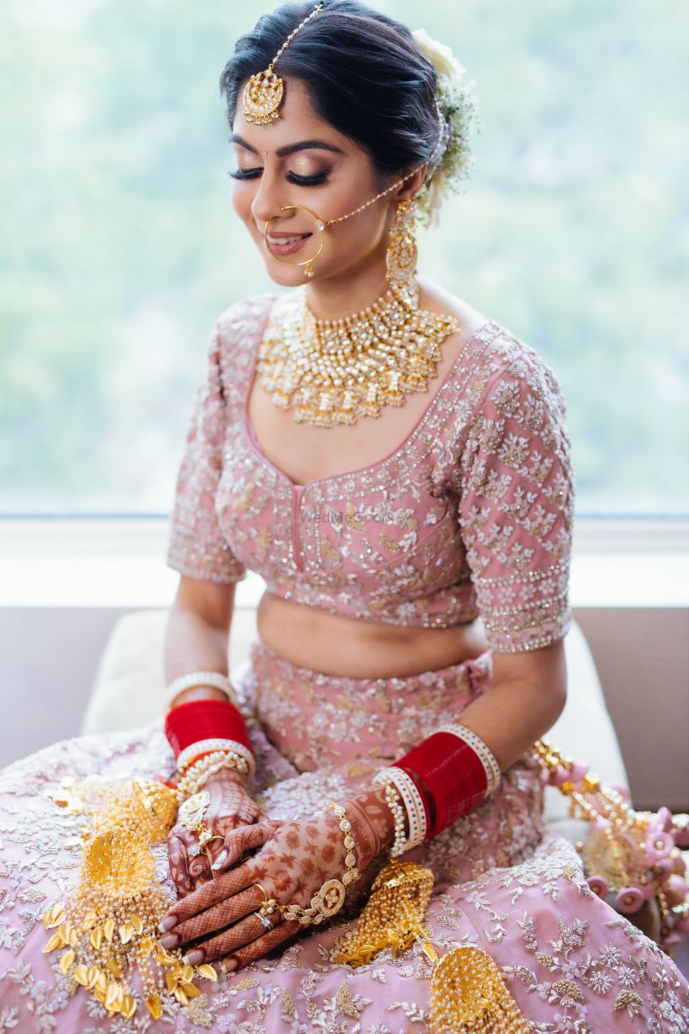 Photo of Bride wearing a pastel pink lehenga with a choker necklace.