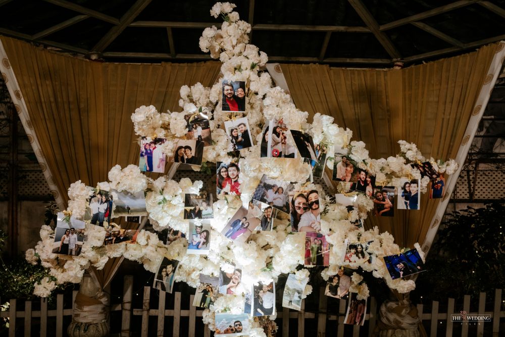 Photo of couple photos hung from beautiful white tree prop inside the wedding