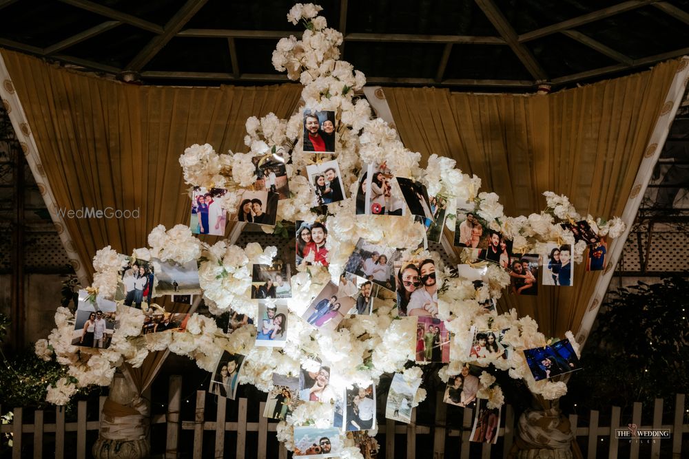 Photo of couple photos hung from beautiful white tree prop inside the wedding