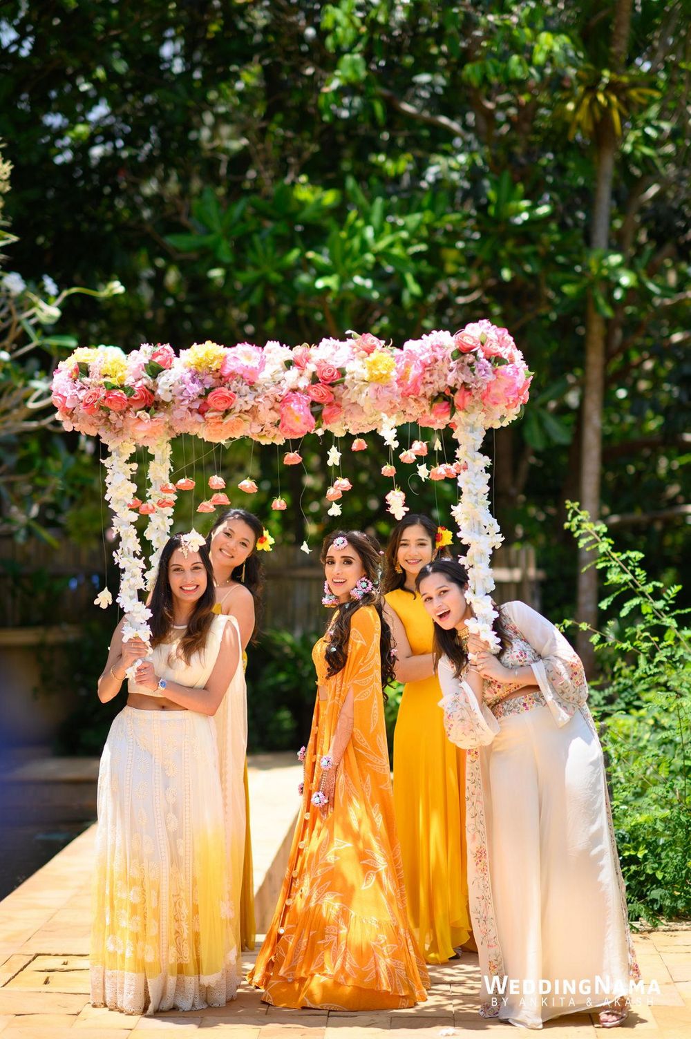 Photo of Bride making her entry with her bridesmaids under a beautiful phoolon ki chaadar.