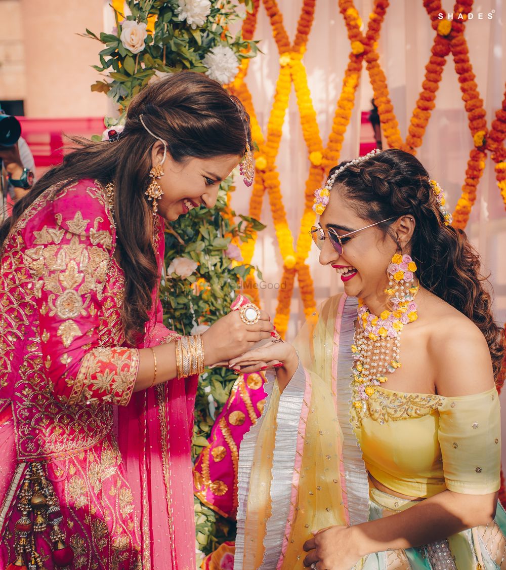 Photo of Bridesmaid applying mehndi on the bride's hand.