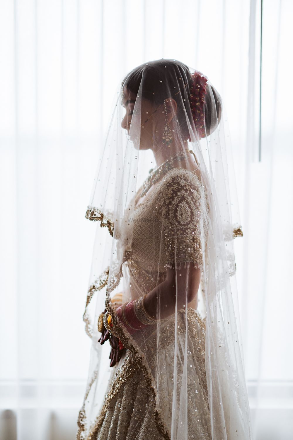 Photo of bridal portrait in white and gold lehenga with dupatta as veil