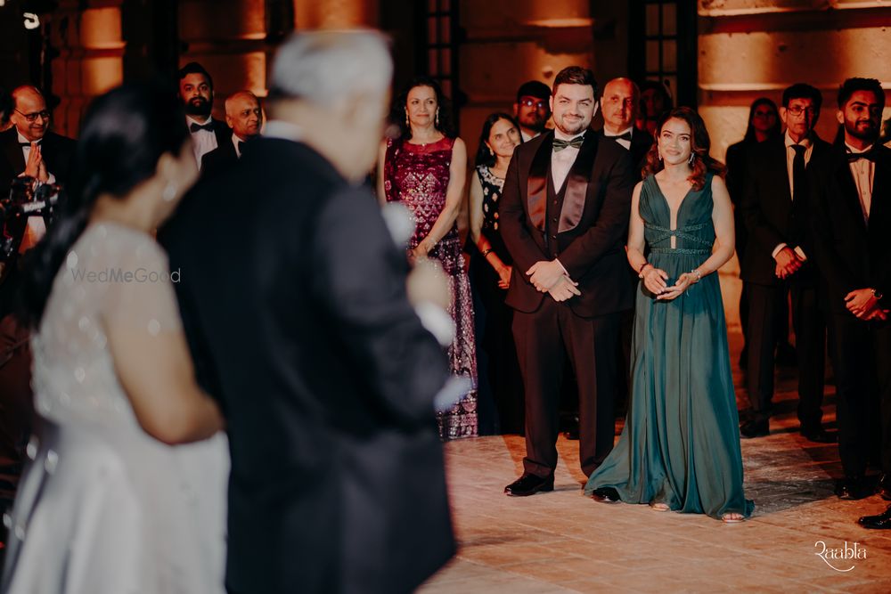 Photo of Candid capture of the bride and groom as they look to the father of the bride giving a speech