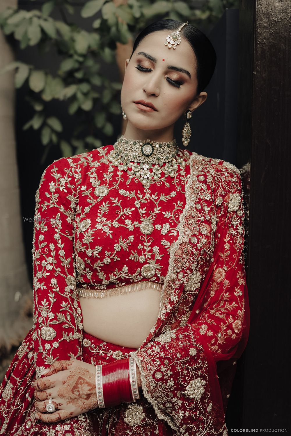 Photo of Wedding day portrait with bride in a metallic eye makeup look and a full sleeved bridal blouse in all red