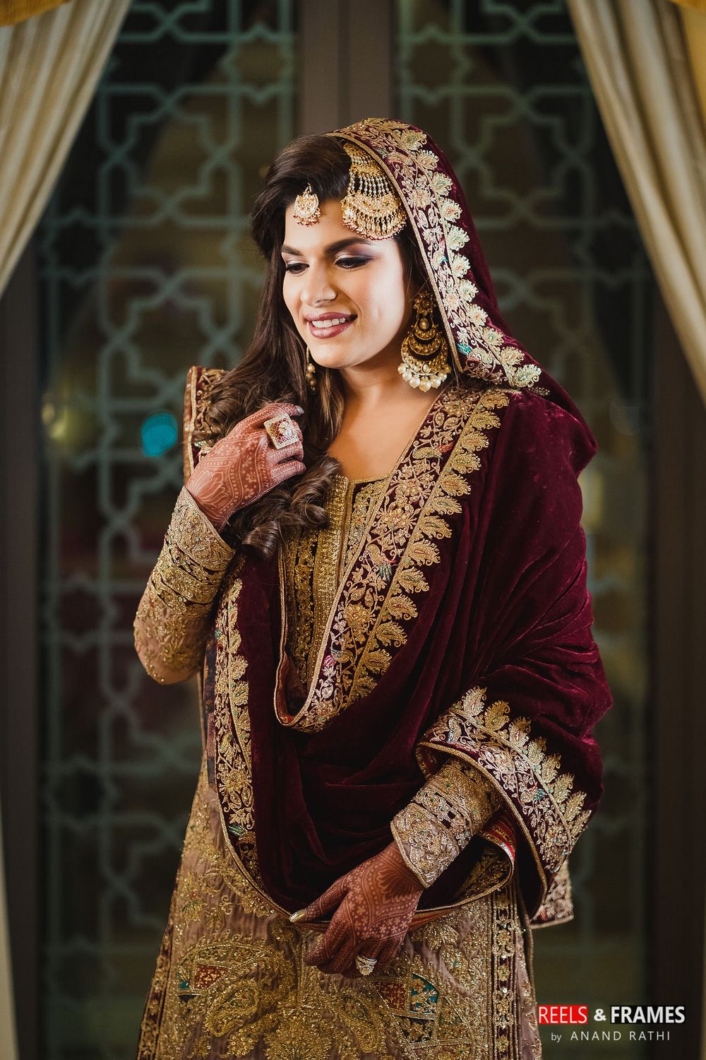 Photo of A bride in a maroon and gold velvet sharara