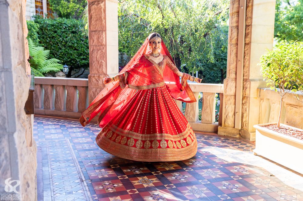 Photo of twirling bridal shot in red classic lehenga