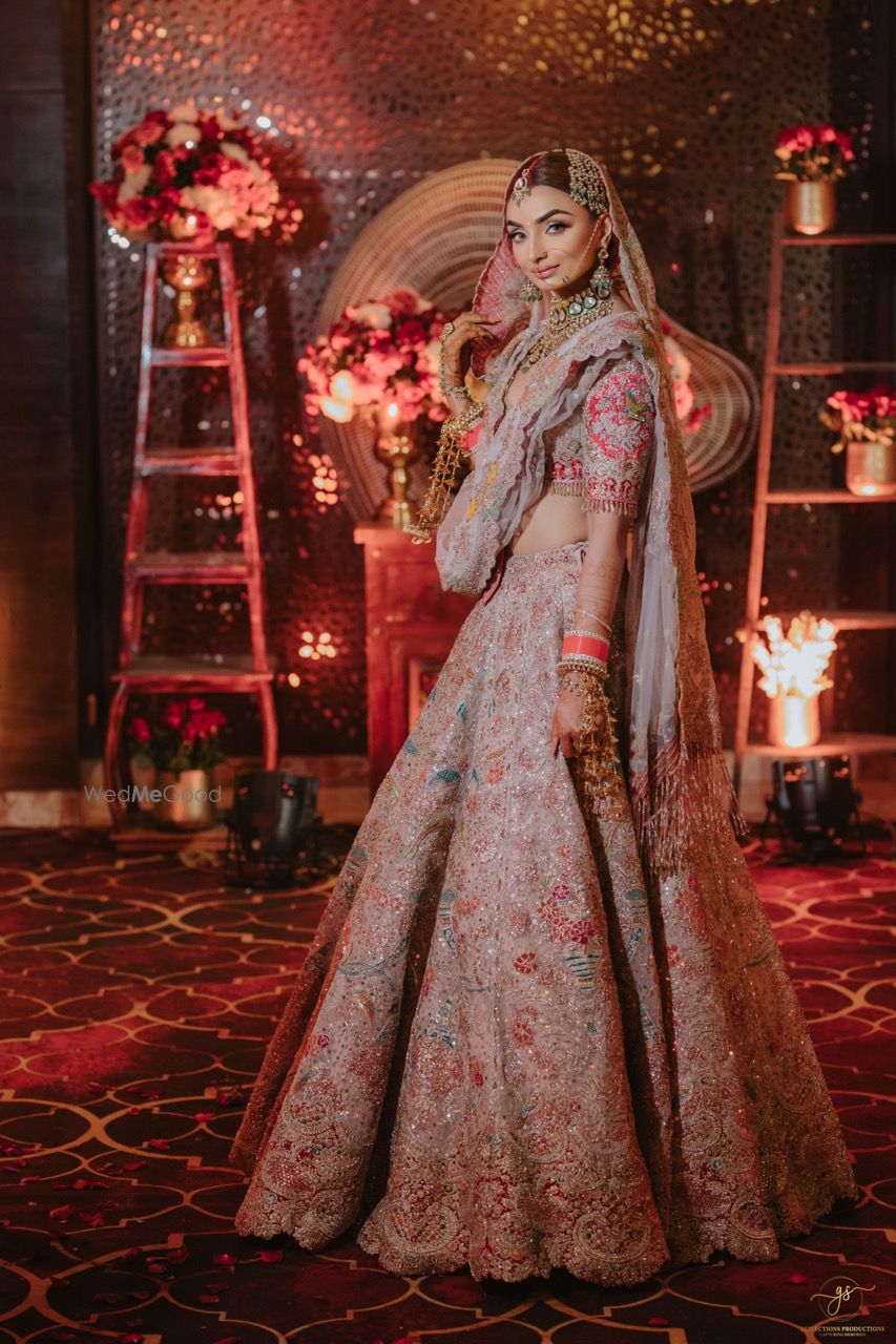 Photo of Classic bridal portrait with the bride in a light pink and red lehenga with heavy work