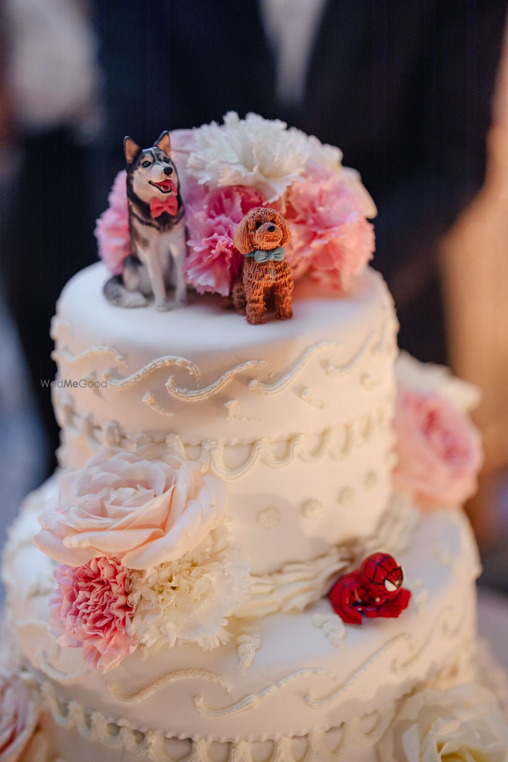 Photo of Cute wedding cake with florals and two dogs as cake toppers