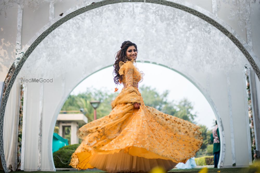 Photo of Bride twirling in yellow mehendi lehenga with ruffled blouse