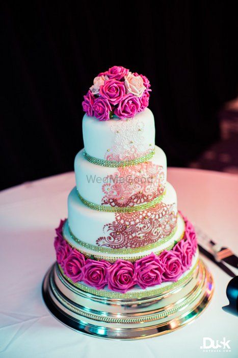 Photo of white and magenta wedding cake with roses