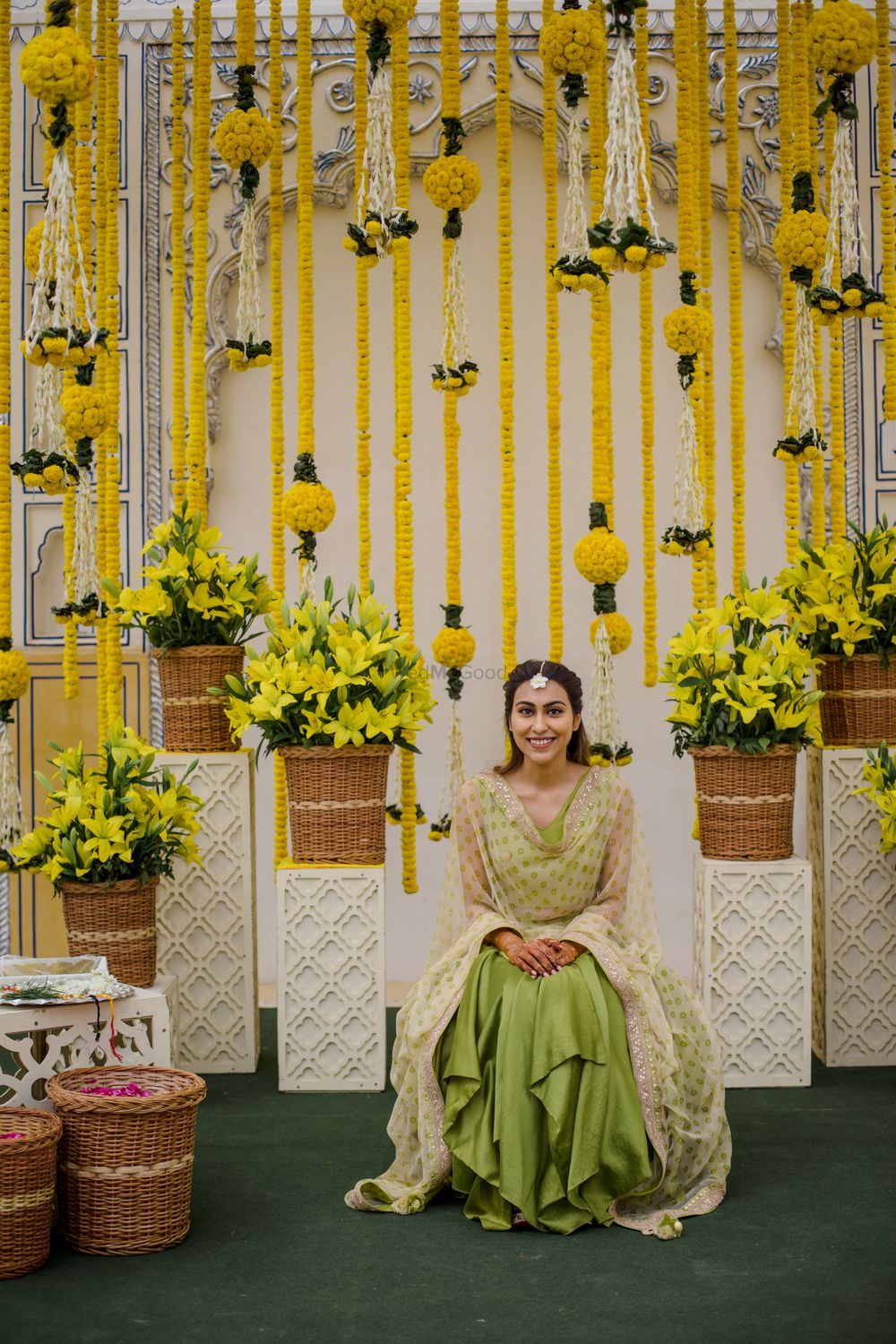 Photo of Bride sitting against a genda phool backdrop.