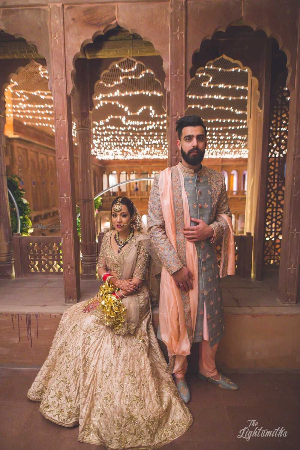 Photo of Bride in beige lehenga and groom in slate blue sherwani