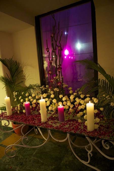 Photo of clustered table setting with candles and purple petals