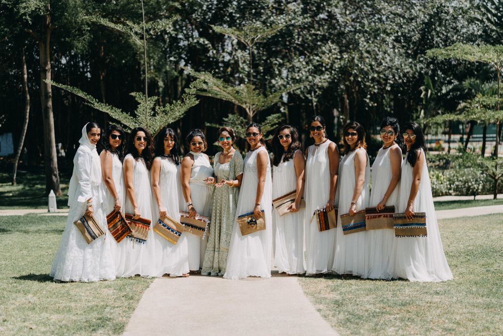 Photo of A bride poses with her bridesmaids in coordinated outfits