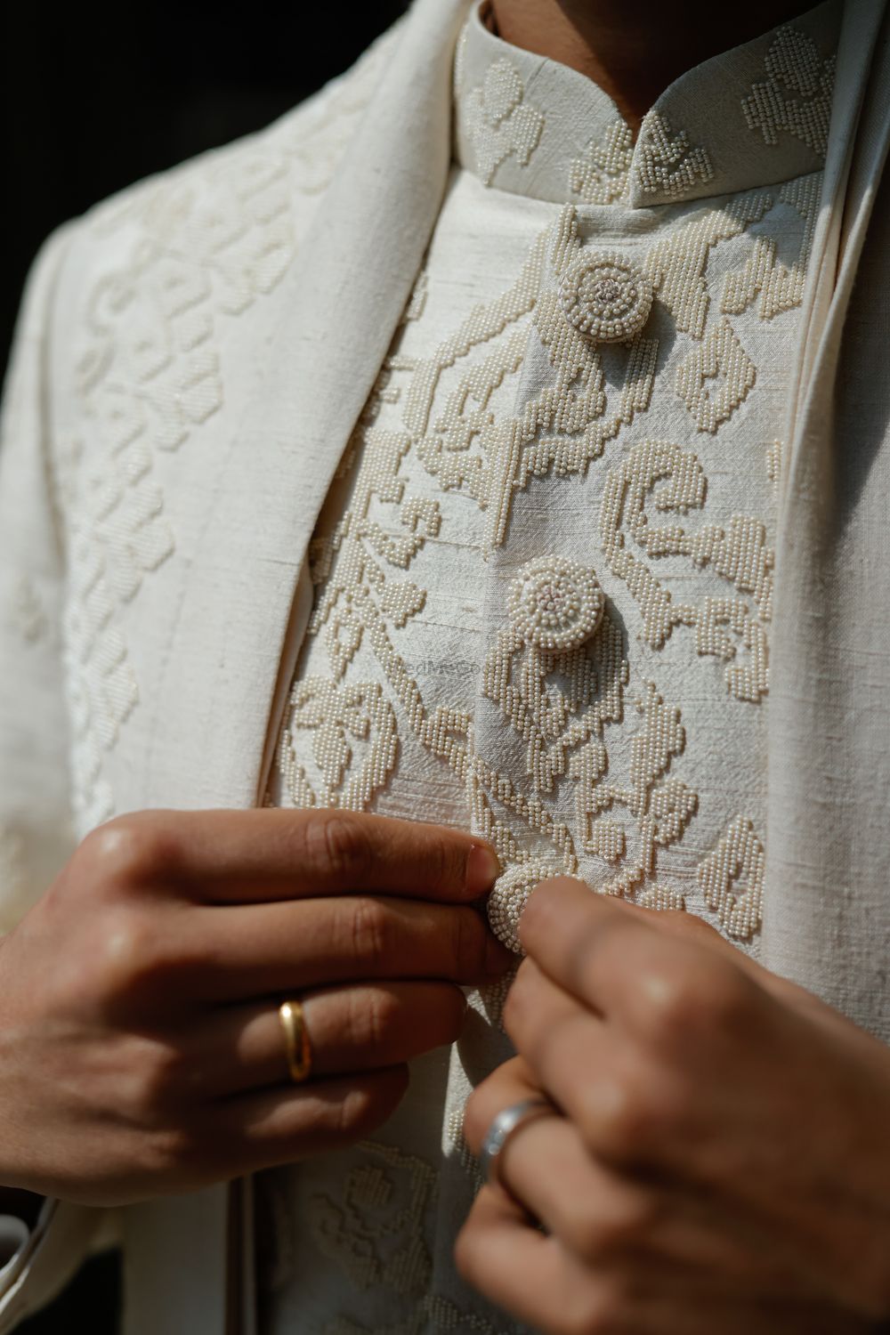 Photo of Gorgeous close up shot of the intricate pearl embroidery for the groom sherwani in ivory.