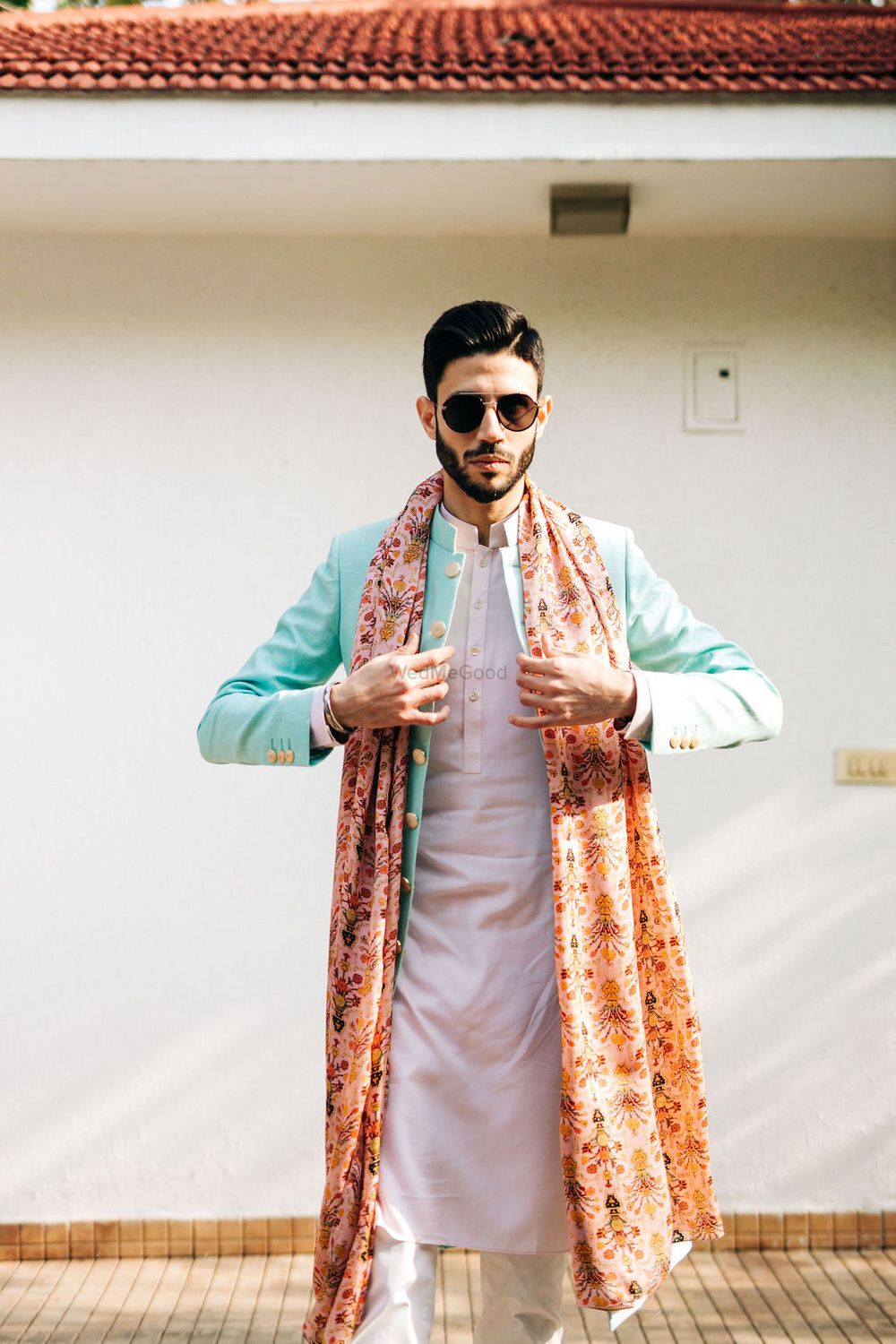 Photo of The groom on mehendi in a white kurta with blue jacket and multicoloured dupatta