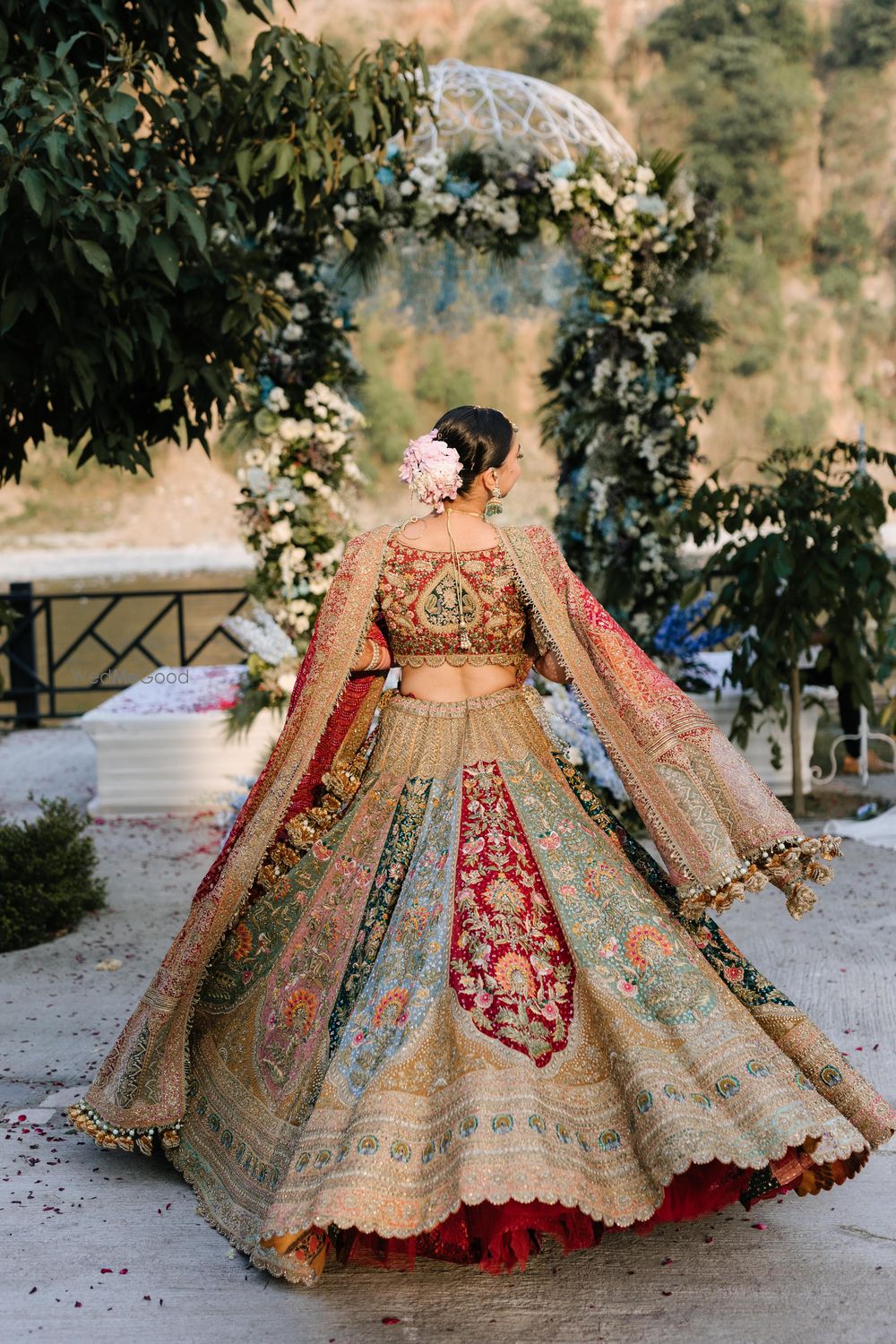 Photo of Twirling bride in a multi-coloured panelled bridal lehenga with an embroidered red dupatta and a heavy blouse.