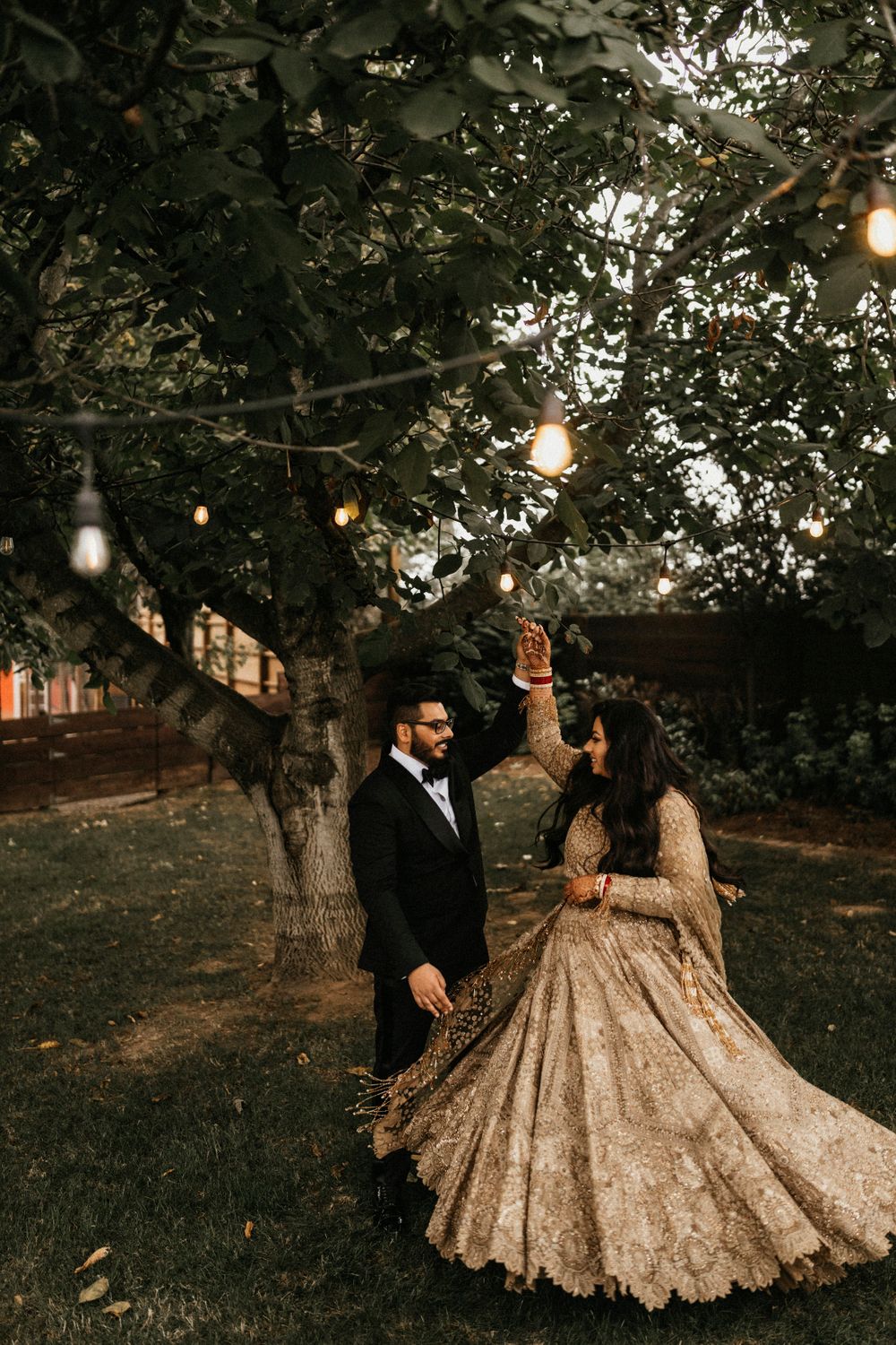 Photo of couple on reception with bride twirling in golden lehenga