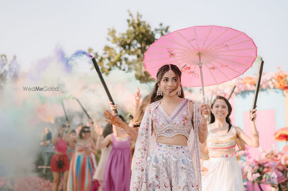 Photo of Beautiful shot of the bride entering with her bridesmaids on the mehendi day under pink parasols and colourful smokebombs