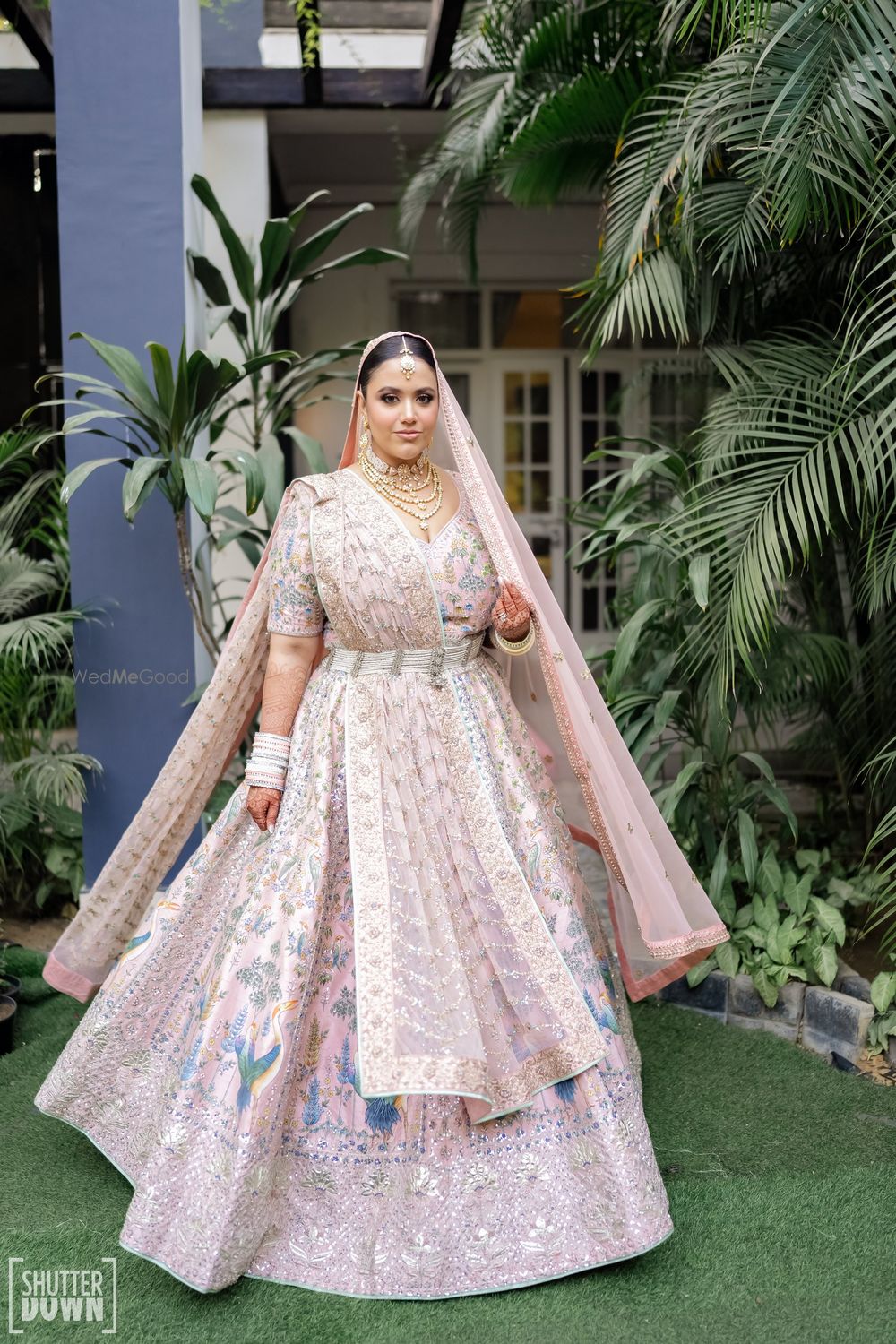 Photo of Bride twirling in a pastel pink wedding lehenga