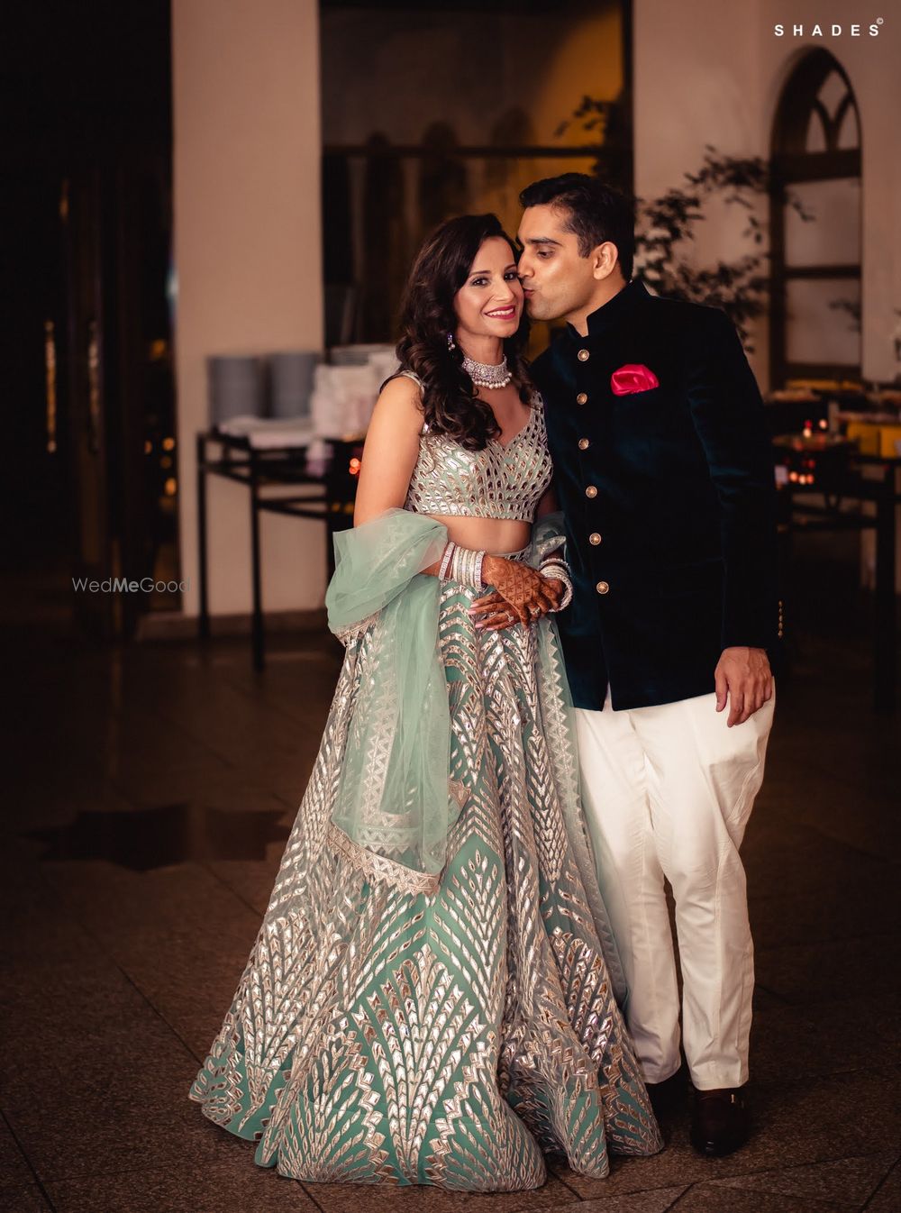 Photo of A bride in a shimmer lehenga posing with her groom-to-be at their sangeet