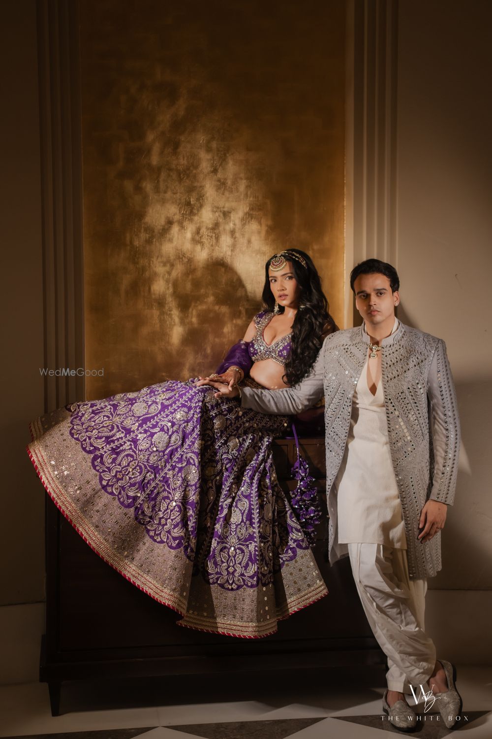 Photo of Bride and groom couple portrait on sangeet night with the bride in a statement mang tika and purple hued lehenga
